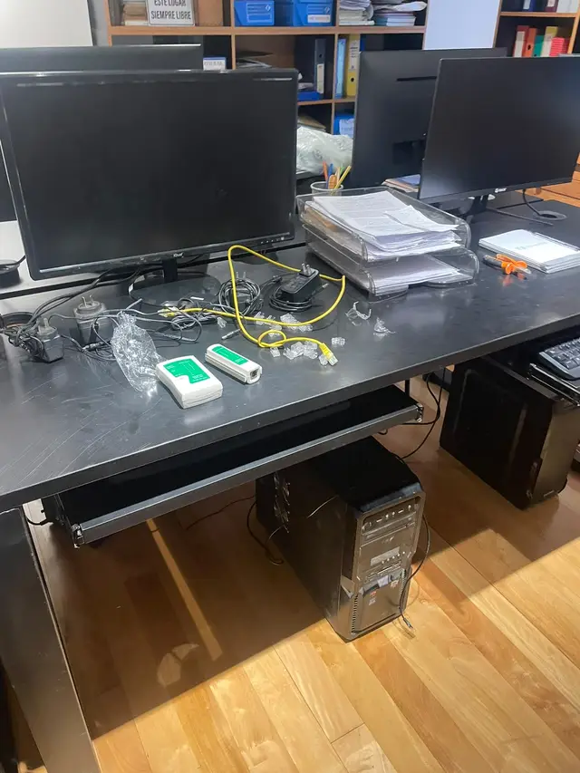 Escritorio con cables de red, fichas y tester durante el armado de puestos