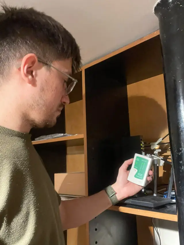 Técnico de RosarioIT probando un cable de red con un tester junto al router
